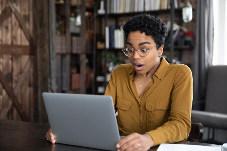 A person looking at a laptop looking surprised.